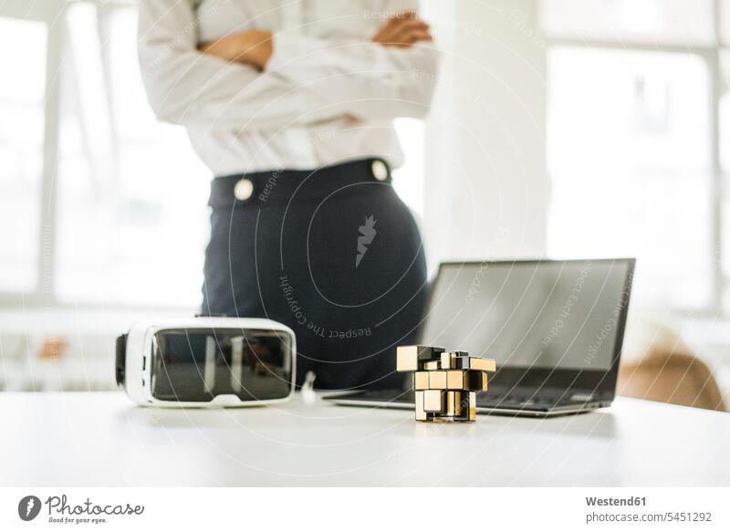 Cubical structure, VR glasses and laptop on office desk with businesswoman in background businesswomen business woman business women specs Eye Glasses