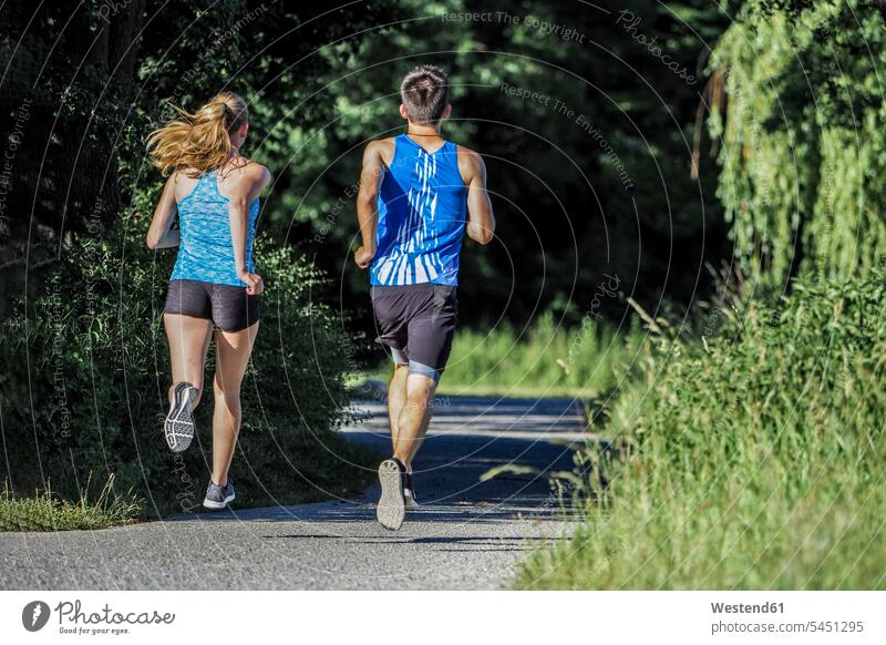 Back view of young couple jogging in park Jogging twosomes partnership couples fitness sport sports people persons human being humans human beings running