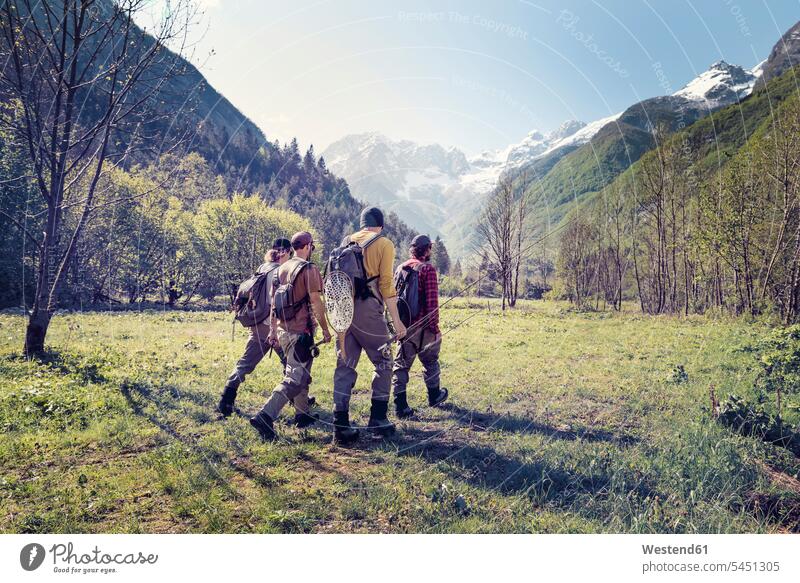 Slovenia, Bovec, four anglers walking on meadow towards Soca river meadows hiking hike going man men males friends Adults grown-ups grownups adult people