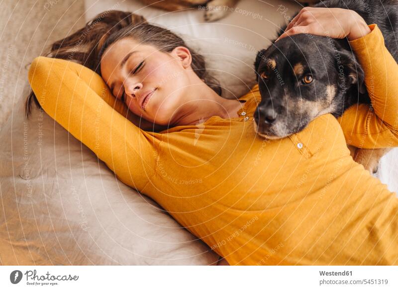 Woman lying in bed with her dog sleeping asleep dogs Canine cuddling snuggle cuddle snuggling embracing embrace Embracement hug hugging woman females women beds
