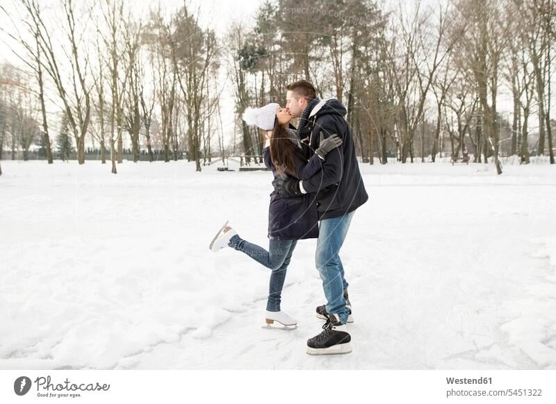 Couple ice skating on a frozen lake, kissing and embracing kisses active couple twosomes partnership couples Ice-Skating lakes winter hibernal embrace