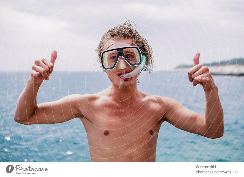 Portrait of smiling young man with diving goggles and snorkel showing Rock And Roll Sign portrait portraits men males snorkels Adults grown-ups grownups adult