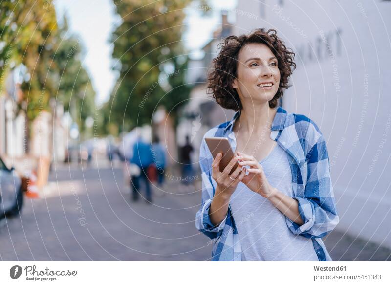 Smiling woman with cell phone in the city smiling smile females women mobile phone mobiles mobile phones Cellphone cell phones Adults grown-ups grownups adult