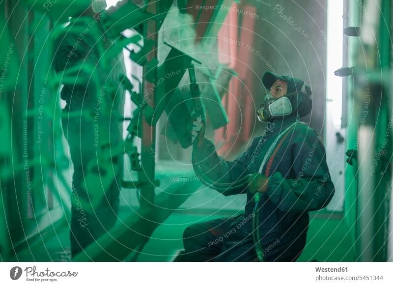 Painters spraying steel components in spray booth of a factory green paint colour color colors Paints colours worker blue collar worker workers