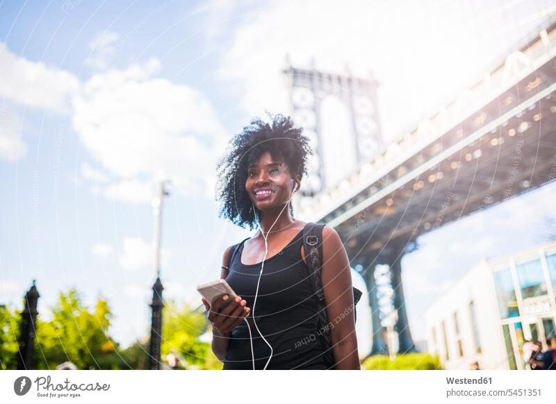 USA, New York City, Brooklyn, smiling woman listening to music at Manhattan Bridge females women hearing smile Adults grown-ups grownups adult people persons