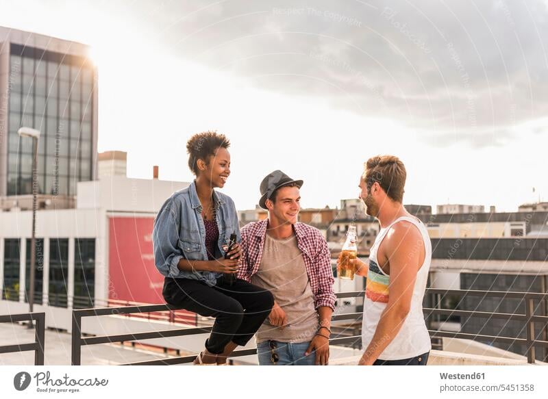 Three friends socializing on a rooftop party celebrating celebrate partying drinking Party Parties Fun having fun funny roof terrace deck Beer Beers Ale