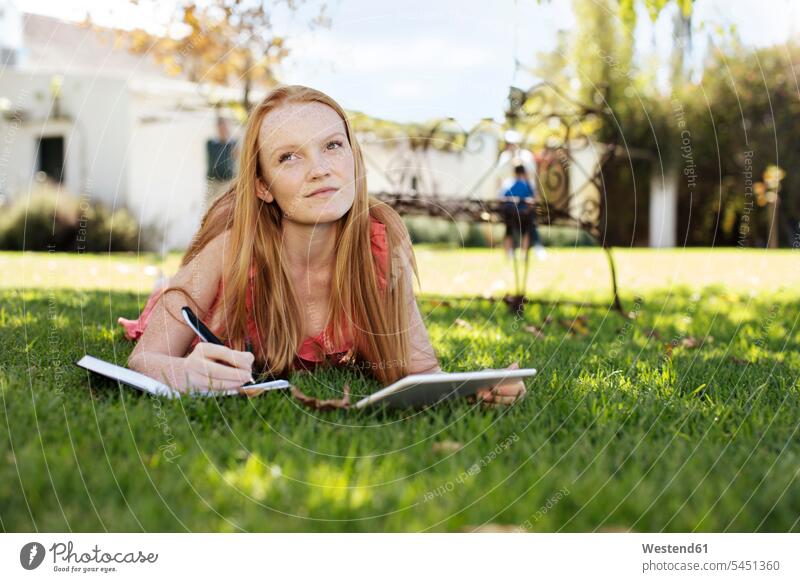 Grl with long red hair lying in grass with tablet and notebook laying down lie lying down digitizer Tablet Computer Tablet PC Tablet Computers iPad