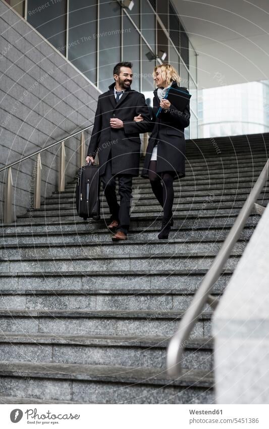 Happy business couple in the city walking down stairs Businessman Business man Businessmen Business men smiling smile businesswoman businesswomen business woman