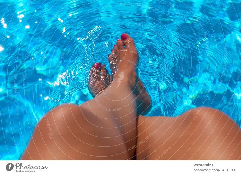 Woman sitting at pool edge with legs in the water swimming pool pools swimming pools human leg human legs woman females women vacation Holidays people persons