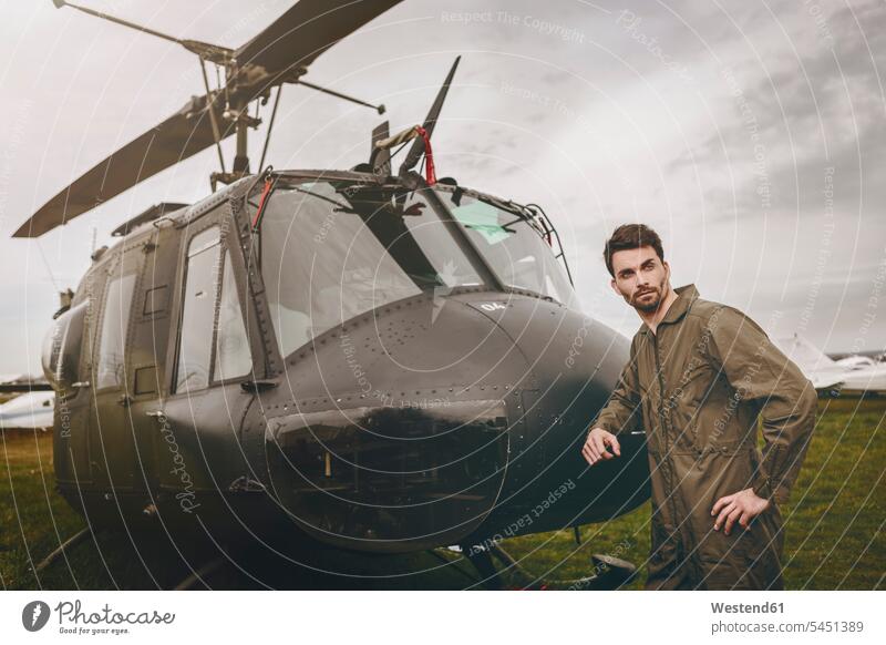 Man in overall standing next to a helicopter pilot pilots aircraft Air Vehicle aircrafts Air Vehicles transportation man men males cool attitude composed