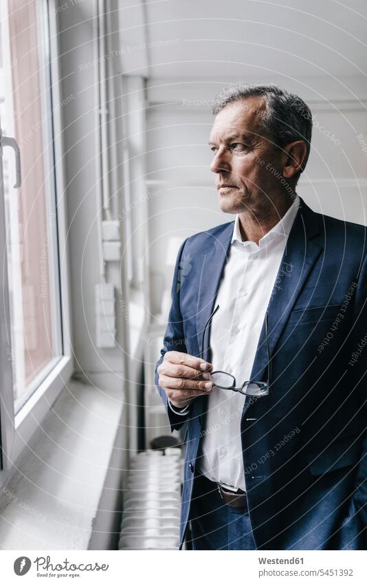Serious mature businessman looking out of window portrait portraits Businessman Business man Businessmen Business men business people businesspeople