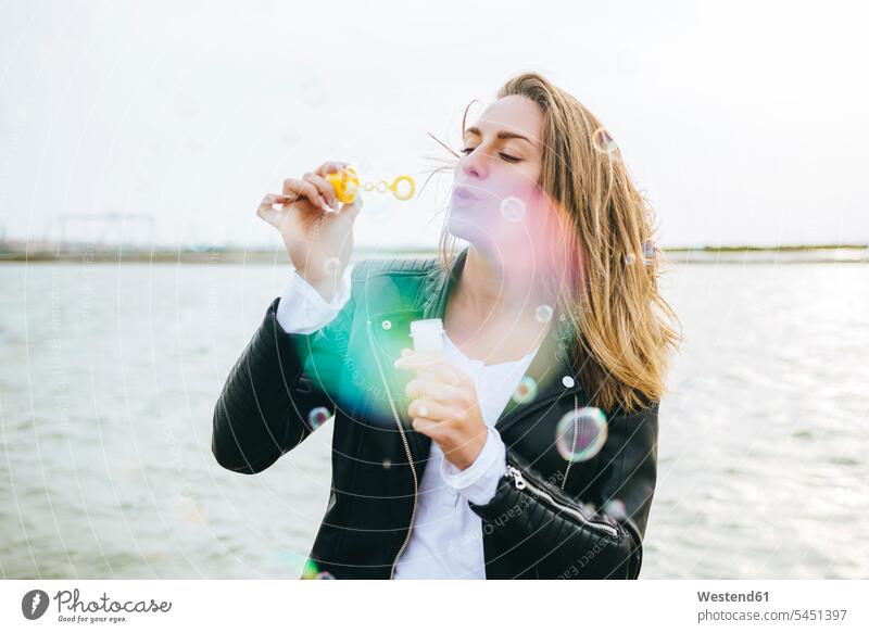 Young woman blowing soap bubbles females women Adults grown-ups grownups adult people persons human being humans human beings enjoying indulgence enjoyment