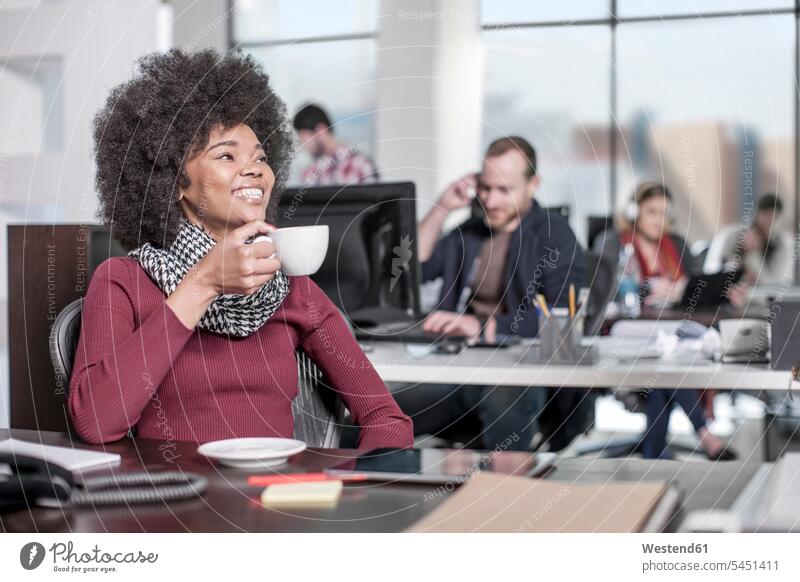 Smiling woman at desk in office drinking coffee offices office room office rooms Coffee smiling smile females women workplace work place place of work Drink