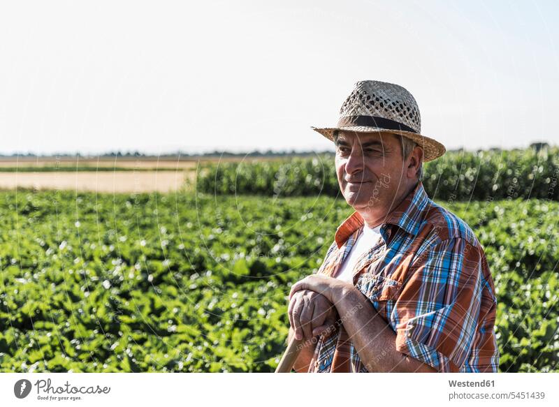 Portrait of smiling senior farmer standing in front of a field agriculturists farmers portrait portraits agriculture man men males Field Fields farmland