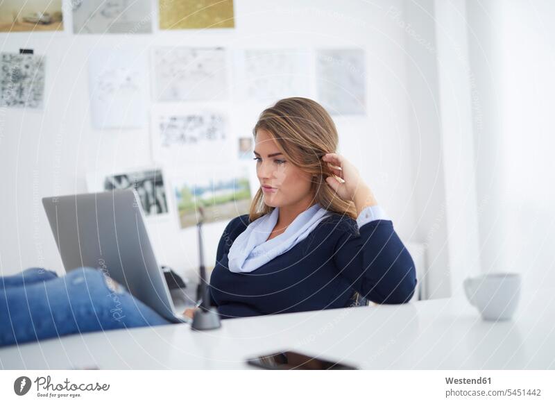 Young woman using laptop at desk in office working At Work caucasian caucasian ethnicity caucasian appearance European online Office Offices watching looking