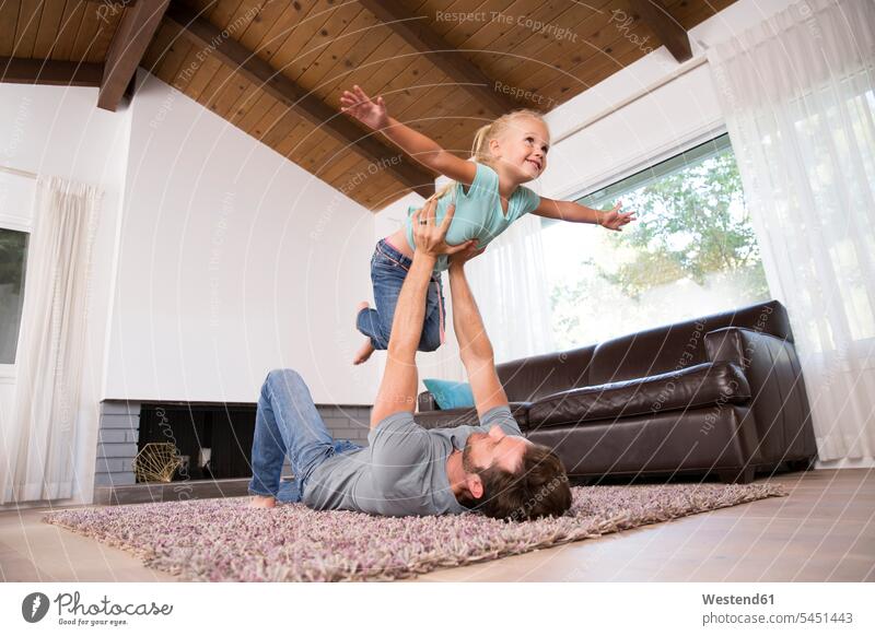 Father playing with daughter on carpet in living room at home father pa fathers daddy dads papa living rooms livingroom daughters carpets rug rugs parents