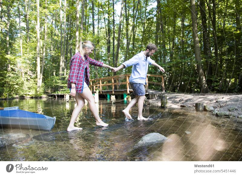 Young couple crossing a forest brook twosomes partnership couples woods forests brooks rivulet people persons human being humans human beings water waters