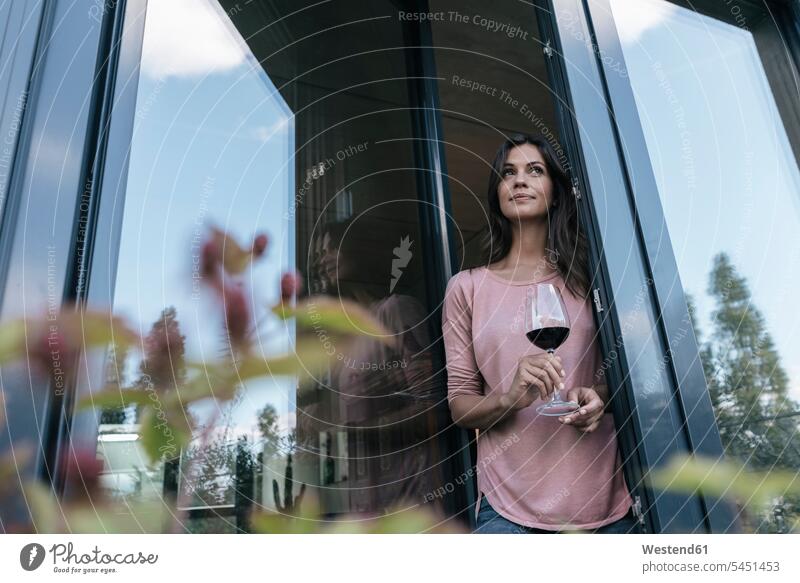 Woman holding glass of red wine looking out of window relaxed relaxation woman females women Red Wine Red Wines windows relaxing Adults grown-ups grownups adult