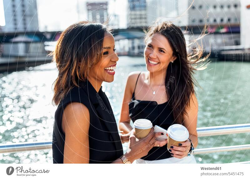 Two happy women having a coffee break on a bridge in the city Coffee woman females Female Colleague laughing Laughter Drink beverages Drinks Beverage