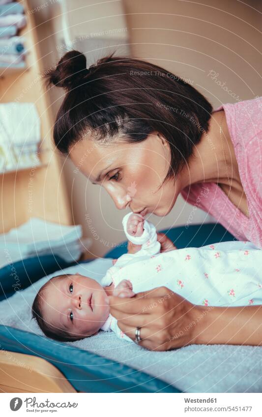 Mother kissing her newborn baby girl's hand in hospital room infants nurselings babies mother mommy mothers ma mummy mama newborns newborn child people persons