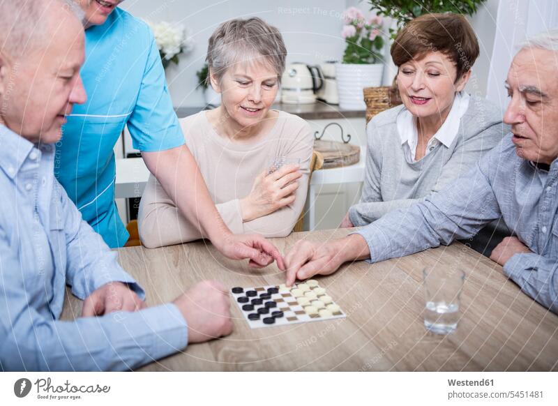 Nurse helping with a games evening for elderly people geriatric nurse playing happiness happy senior adults seniors old nursing staff Carer