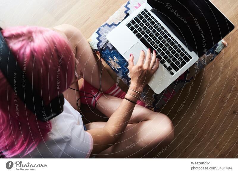 Young woman with pink hair wearing headphones and using laptop at home Laptop Computers laptops notebook headset females women computer computers Adults