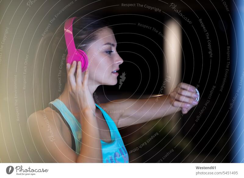 Young woman with pink headphones checking her smartwatch exercising exercise training practising on the phone call telephoning On The Telephone calling headset