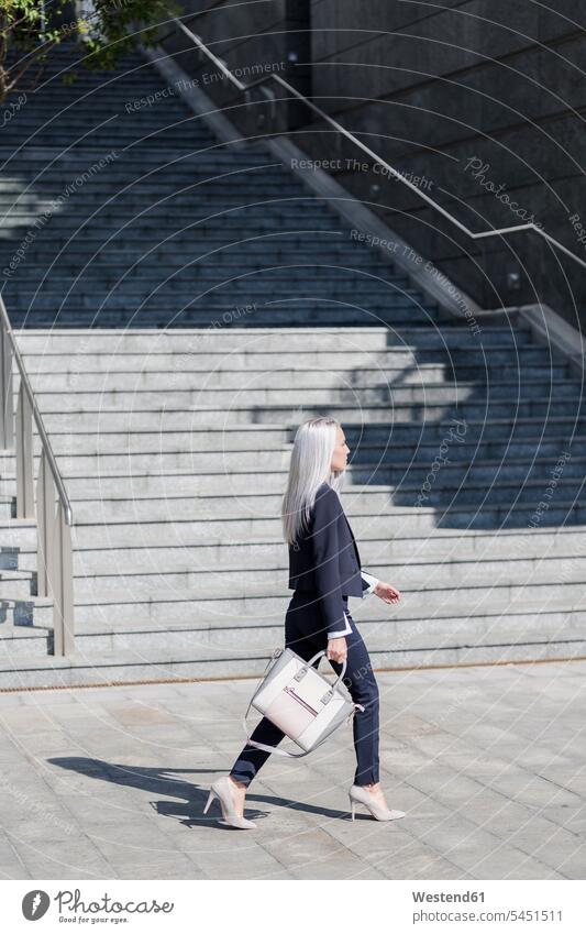Young businesswoman on the go in the city walking going businesswomen business woman business women stairs stairway females business people businesspeople