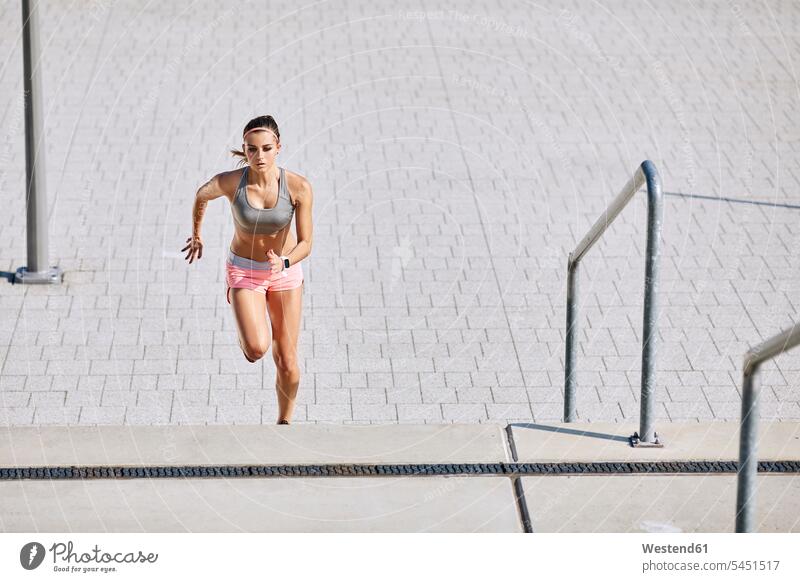 Fit young woman running on stairs exercising exercise training practising stairway females women fit Adults grown-ups grownups adult people persons human being