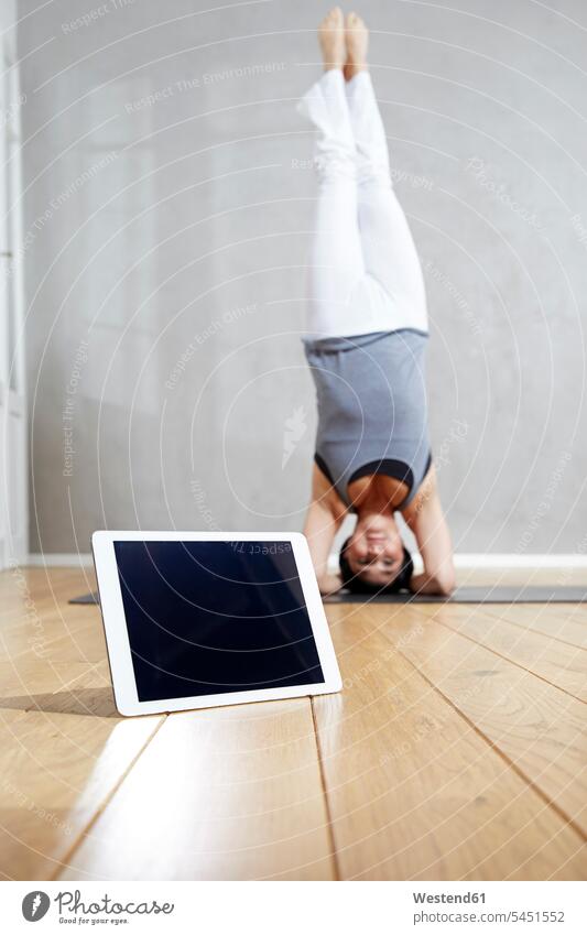 Woman practising yoga doing a headstand behind tablet Yoga exercise exercises woman females women headstands digitizer Tablet Computer Tablet PC