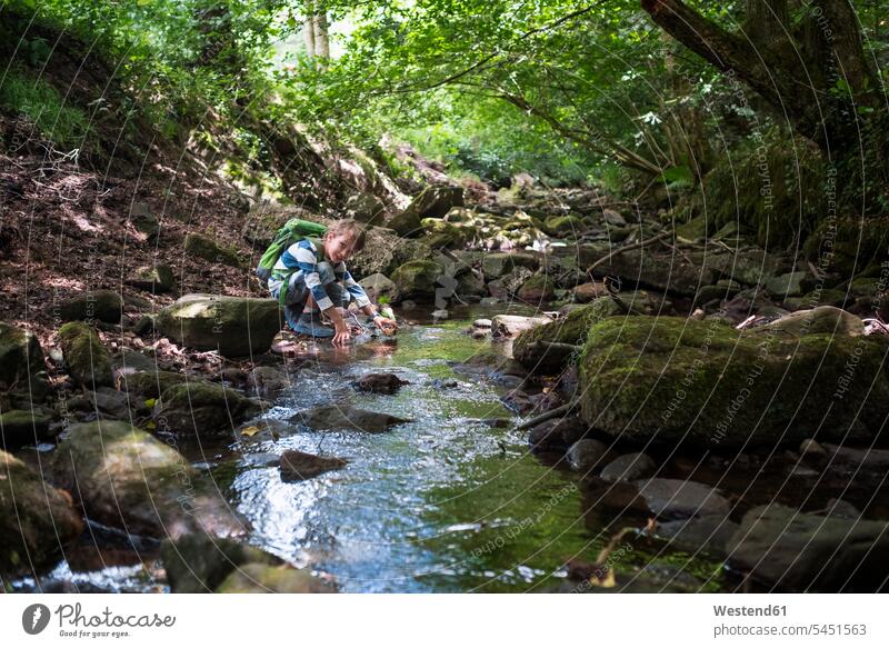 Little boy playing at brook in the woods boys males child children kid kids people persons human being humans human beings smiling smile water's edge waterside