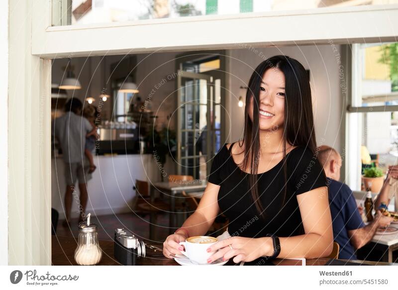 Happy asian woman in a coffee shop next to the window female Asian female Asians females women drinking Coffee cafe smiling smile windows Asian Ethnicity people
