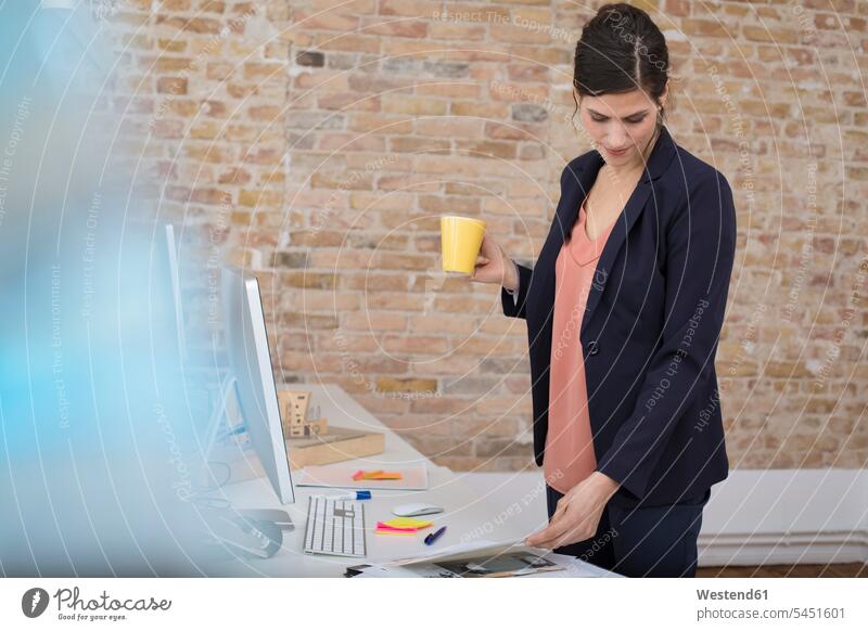 Businesswoman standing at desk in office offices office room office rooms desks looking eyeing businesswoman businesswomen business woman business women