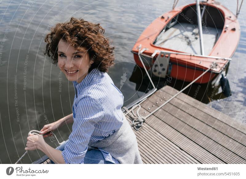 Woman standing on jetty with moored sailing boat boats landing stage landing stages woman females women lake lakes jetties leisure free time leisure time