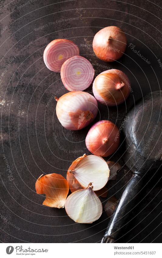 Sliced and whole pink onions on rusty ground rusting rusted onion skin onion skins wooden spoon wooden spoons Brown Background brown dark background Allium Cepa