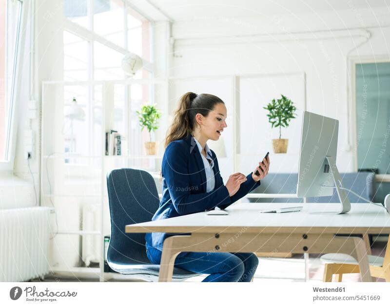 Businesswoman at desk checking cell phone sitting Seated businesswoman businesswomen business woman business women desks females mobile phone mobiles