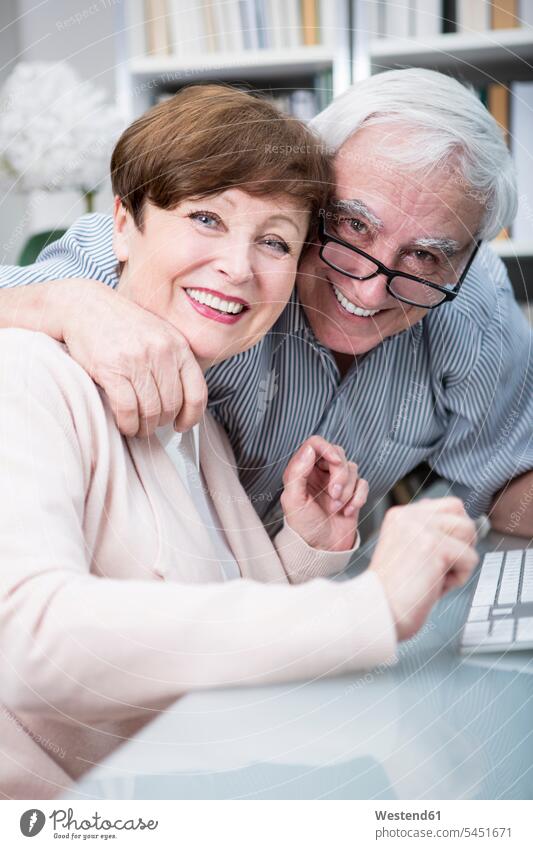 Senior couple embracing and smiling at camera computer computers carefree confidence confident togetherness age toothy smile big smile open smile laughing