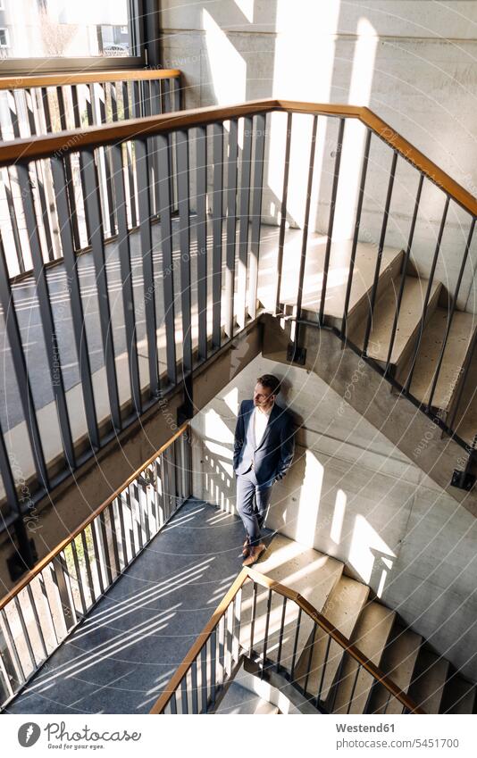 Businessman standing in staircase Business man Businessmen Business men business people businesspeople business world business life staircases stairwell Light