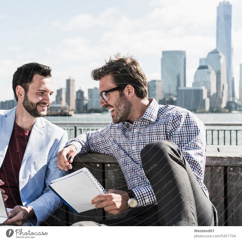 USA, two businessmen working at New Jersey waterfront with view to Manhattan Businessman Business man Businessmen Business men At Work smiling smile notepad