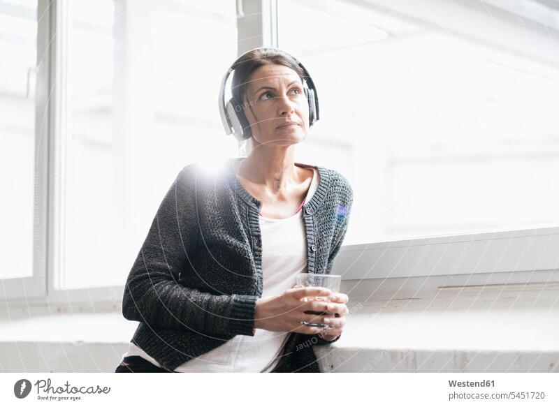 Portrait of woman in a loft listening music with headphones portrait portraits headset females women Adults grown-ups grownups adult people persons human being