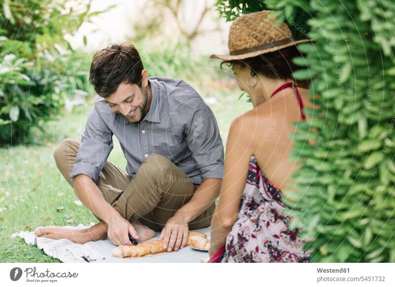 Happy couple having a picnic in a park smiling smile parks twosomes partnership couples Picnic picnicking people persons human being humans human beings Meals