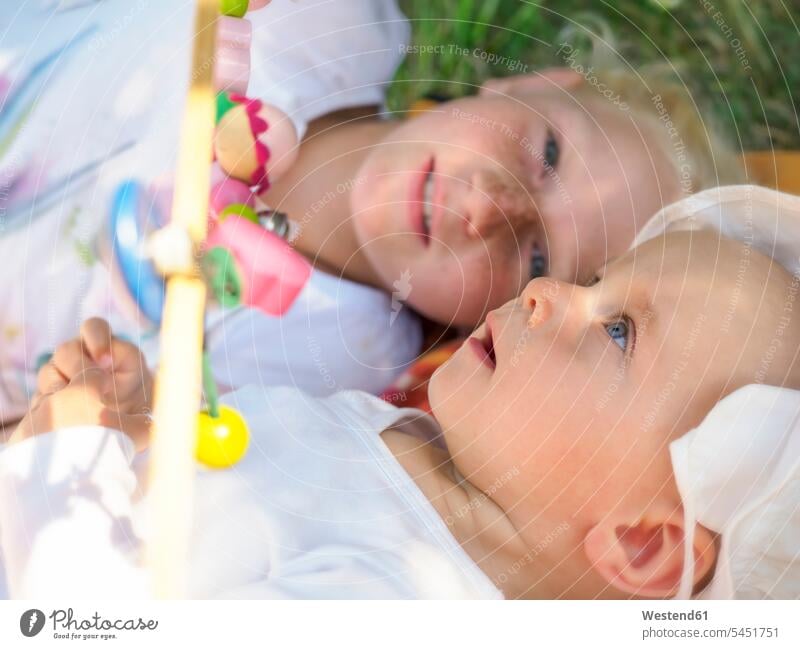 Amazed baby girl lying with her sister on blanket on a meadow portrait portraits baby girls female babies infants people persons human being humans human beings