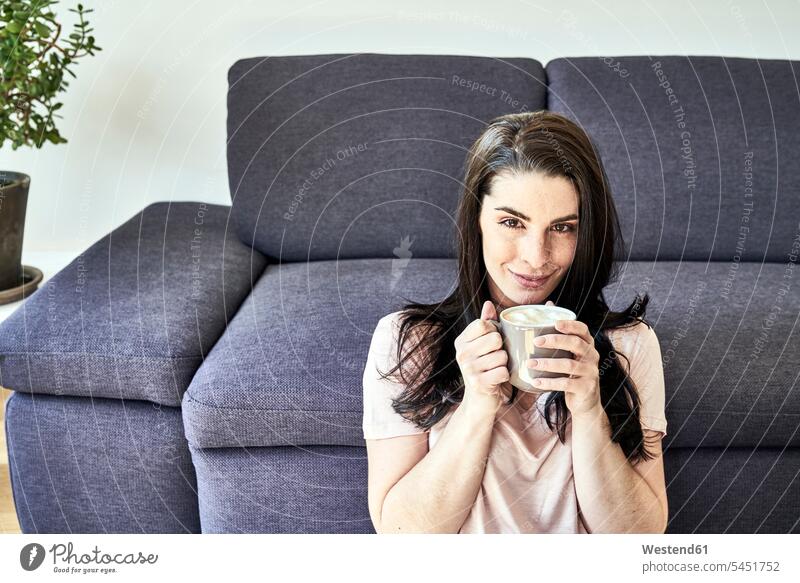 Smiling young woman with coffee mug at home relaxed relaxation Coffee females women smiling smile relaxing Drink beverages Drinks Beverage food and drink