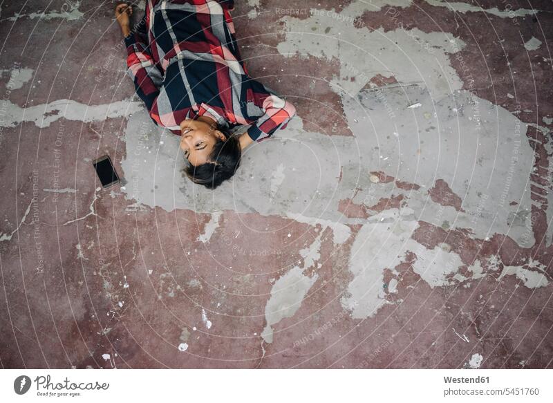 Woman lying on cracked floor with cell phone laying down lie lying down woman females women mobile phone mobiles mobile phones Cellphone cell phones
