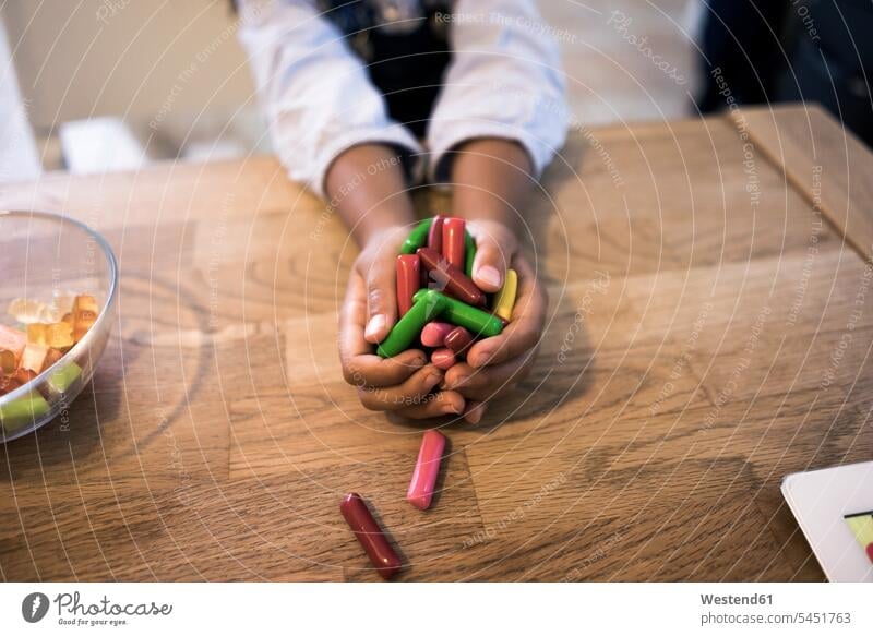 Hands of a little girl holding candies Candies Sweetmeats Candy females girls hand human hand hands human hands nibbling snacking nibble Table Tables Sweets