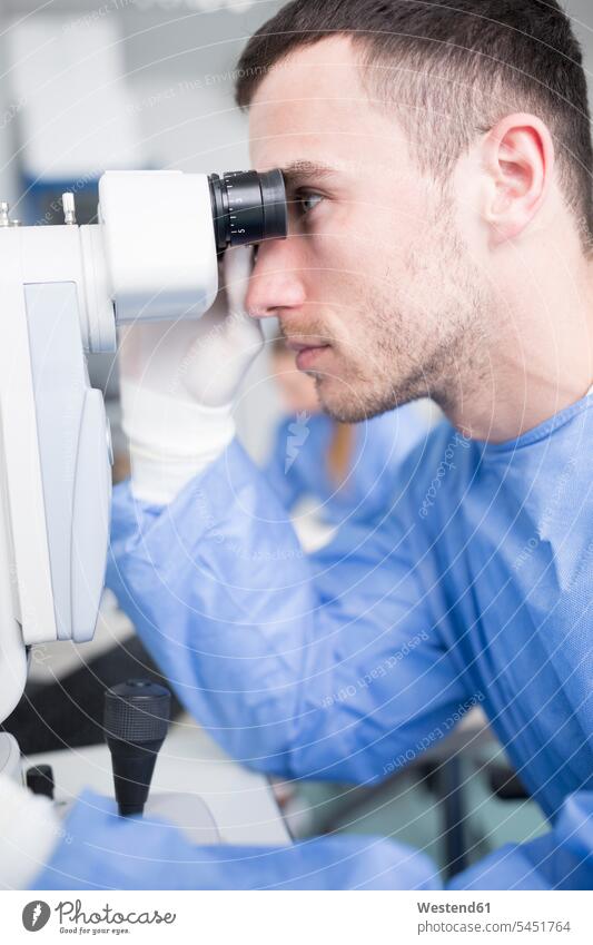 Lab technician looking through microscope laboratory laboratory technician Lab Tech examining checking examine view seeing viewing working At Work microscopes
