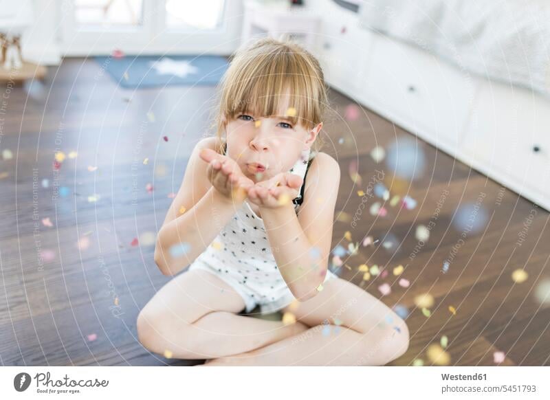 Girl at home sitting on floor blowing confetti Fun having fun funny girl females girls happiness happy child children kid kids people persons human being humans