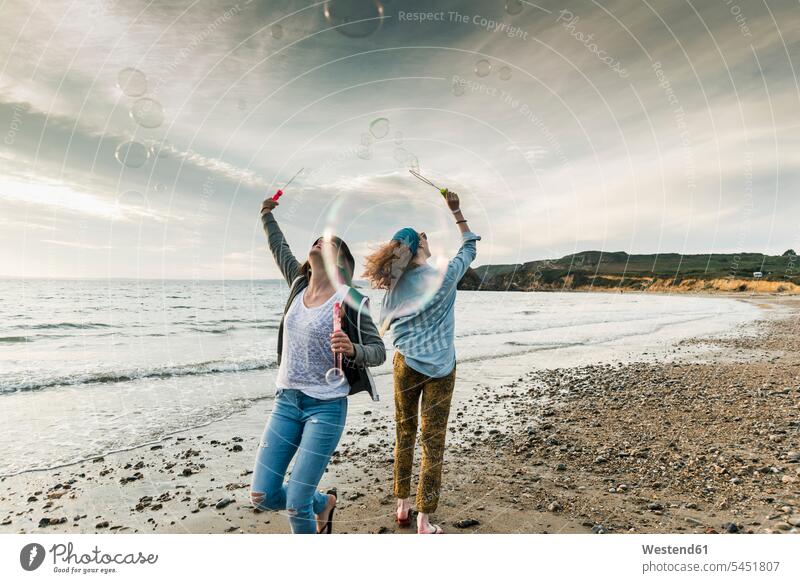 Happy friends making soap bubbles on the beach beaches happiness happy female friends mate friendship vacation Holidays Travel relationship Human Relationship