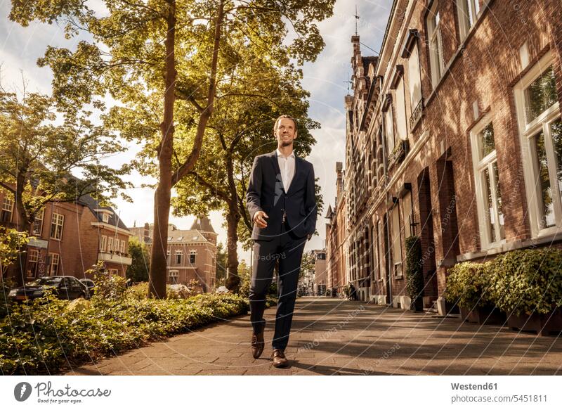 Netherlands, Venlo, confident businessman walking on pavement going Businessman Business man Businessmen Business men city town cities towns Side Walk