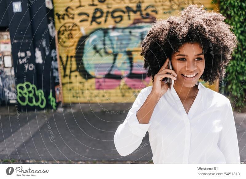 Smiling young woman on cell phone outdoors mobile phone mobiles mobile phones Cellphone cell phones females women standing on the phone call telephoning